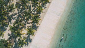 An aerial view of a beach with palm trees and a clear turquoise sea. - NOK Elegant 1BR The Towers by Vistacana (Punta Cana)