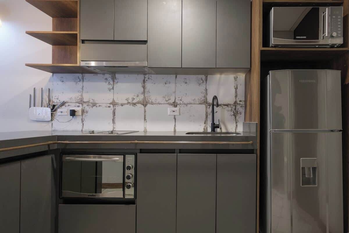 A compact kitchen with a microwave, oven, and refrigerator.