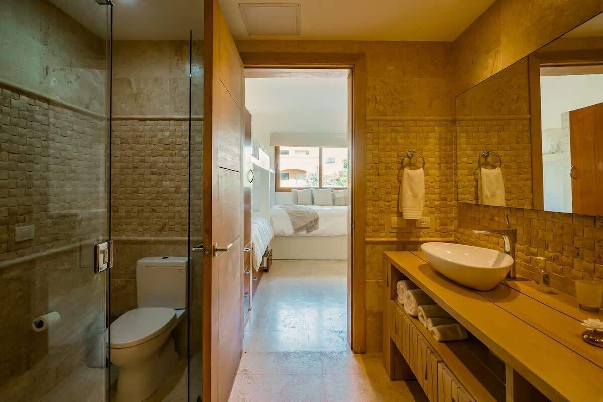 Un baño moderno con ducha envuelta en vidrio, un lavamanos espacioso y un inodoro a la vista.