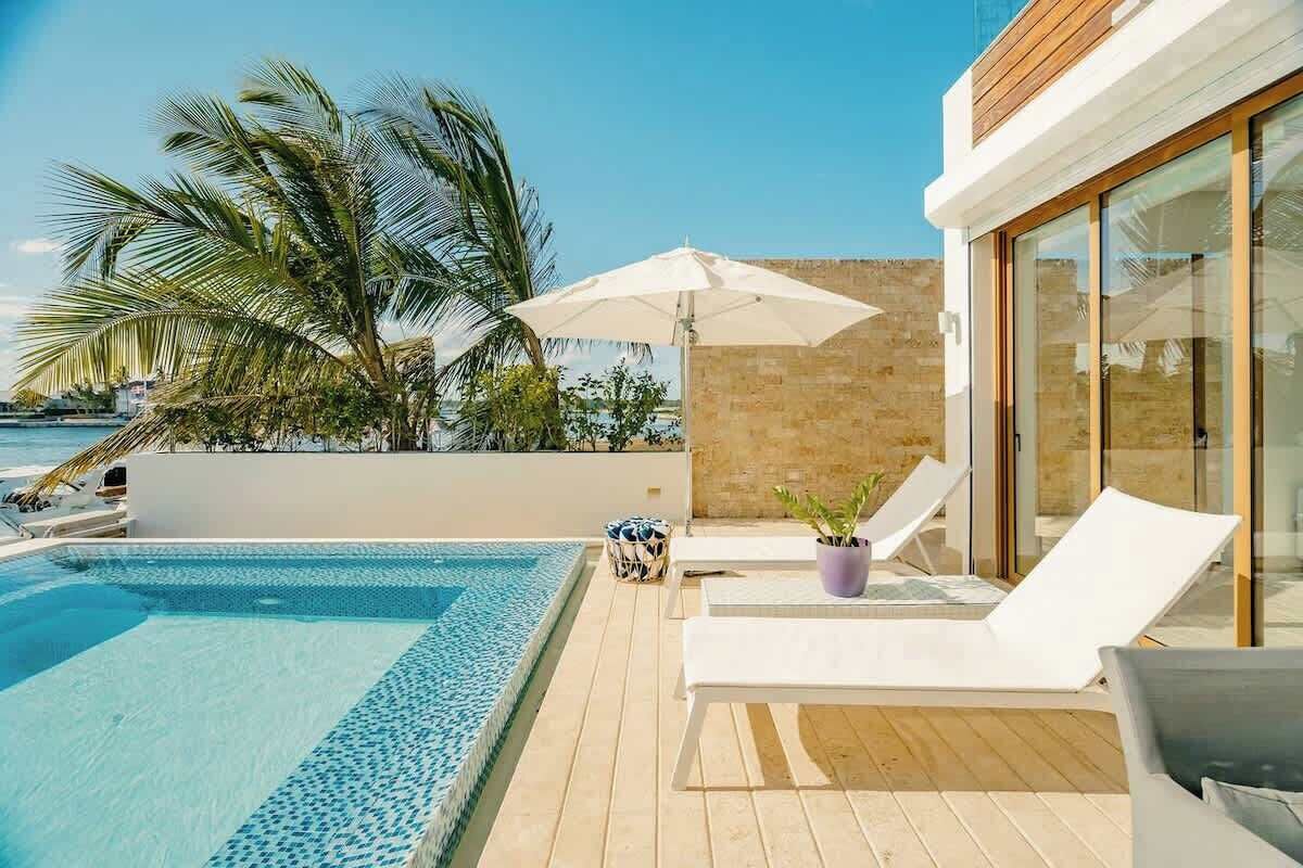 A modern outdoor pool area with lounge chairs, a small table, and a potted plant.