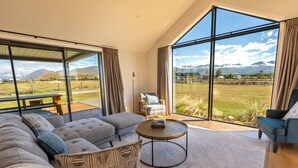 Ein modernes Wohnzimmer mit einer großen Couch, einem Couchtisch und Bergblick durch große Fenster.