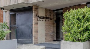 A building entrance with a black gate, a sign reading 'Mambe,' and a brick wall. - NOK Incredible 1 BR in Chapinero (Bogotá)