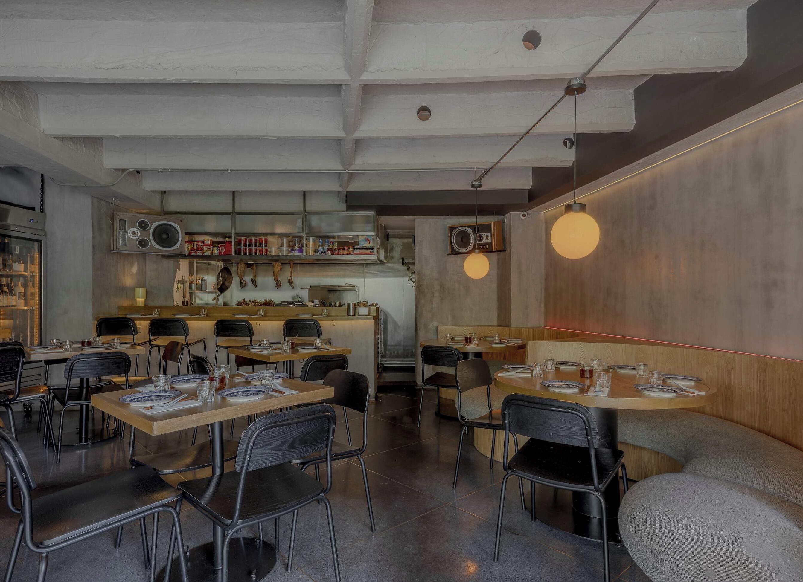 A restaurant interior with exposed ceiling beams, a bar area, and tables set for dining.