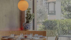 A dining area with a table set for four, a potted plant, and a hanging light fixture. - NOK Centric 1 BR in Chapinero (Bogotá)