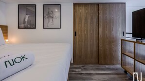 Een slaapkamer met een bed, een houten kledingkast en twee afbeeldingen in lijsten aan de muur.