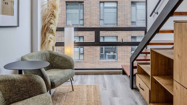 Een modern interieur met een groot raam, een trap en een zithoek met vloerkleed.