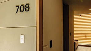En hall med en beige vägg, en dörrkarm och en skylt med siffran ”708”.