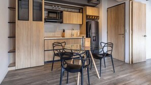 A modern kitchen with wooden cabinets, a glass dining table, and black chairs. - NOK Stunning 1 BR in Chapinero (Bogotá)