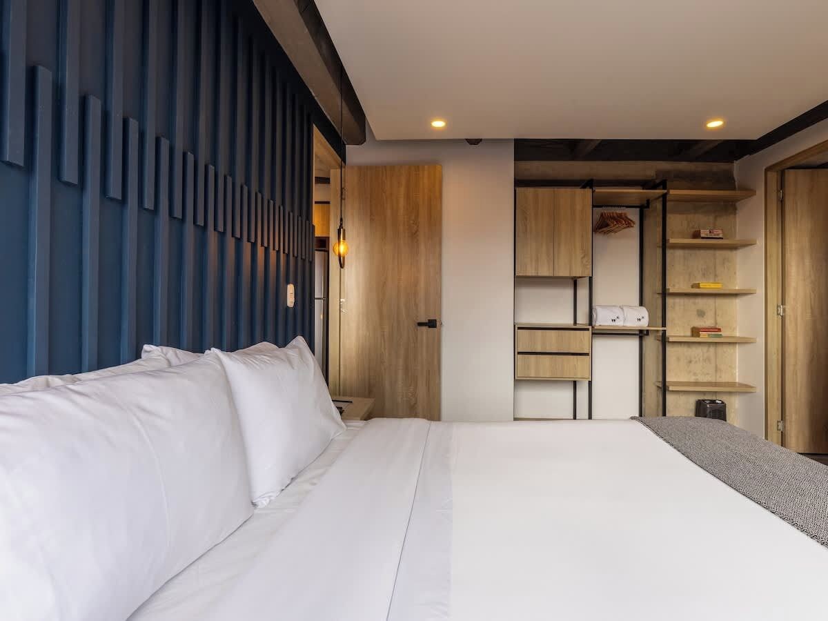 Une chambre d’hôtel moderne dotée d’un grand lit, d’étagères intégrées et d’une armoire en bois.
