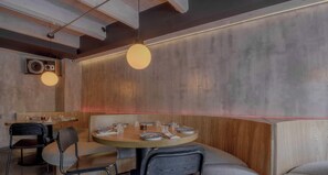 Ein Restaurantinneres mit runden Tischen, Stühlen und Pendelleuchten.