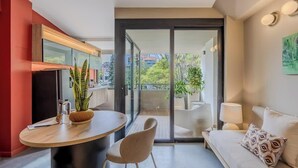 Een moderne woonkamer met een bank, een eettafel en een balkon met uitzicht op de stad.