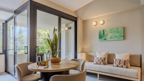 Een moderne woonkamer met een ronde tafel, een bank en een groot raam met uitzicht op groen.