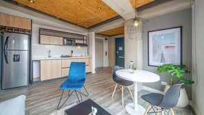 A modern kitchen with wooden cabinets, a stainless steel refrigerator, and a dining area with a round table and chairs. - NOK Bright Loft in Chapinero (Bogotá)