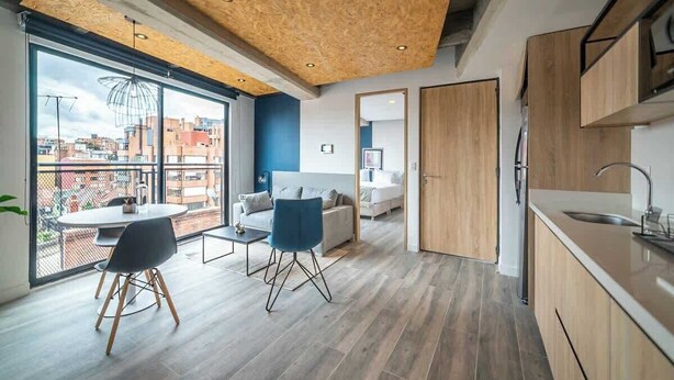 A modern apartment with a dining area, kitchen, and a balcony with a city view. - NOK Bright Loft in Chapinero (Bogotá)