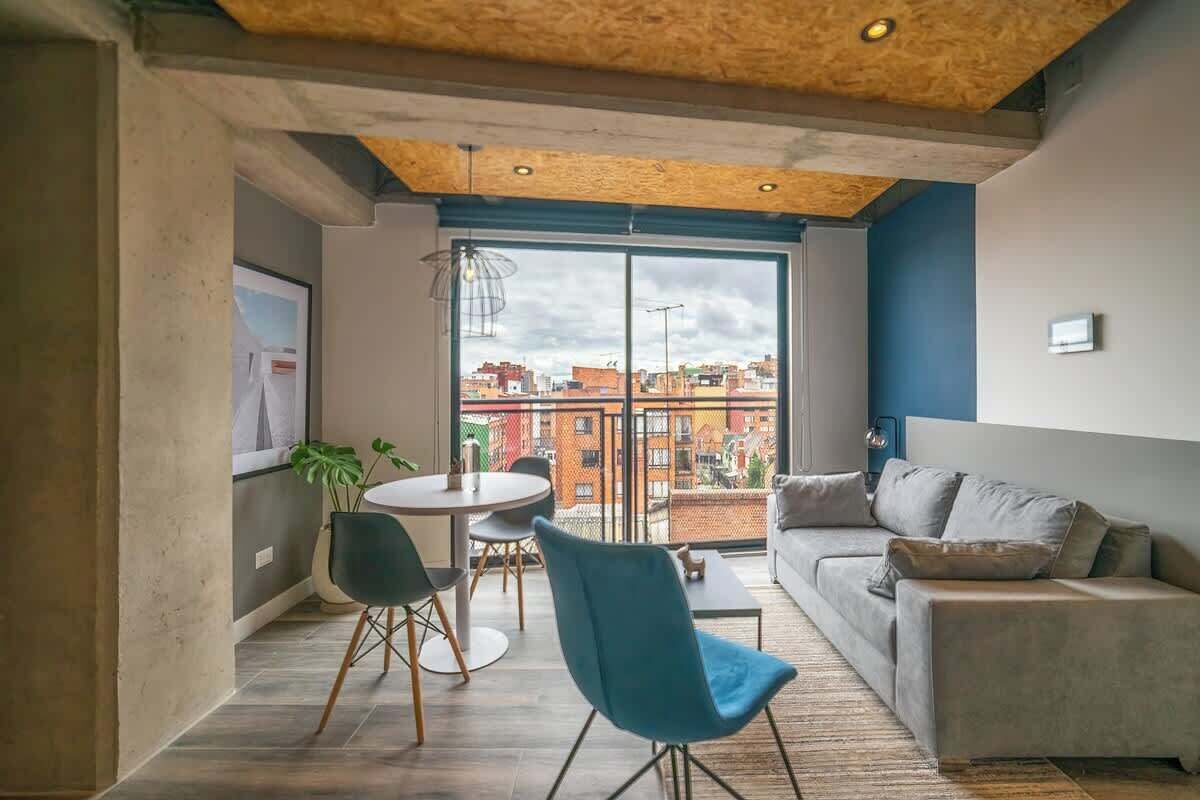Un soggiorno moderno con un divano, un tavolo da pranzo con sedie e un'ampia finestra vista città.