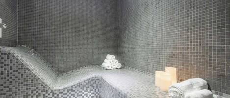 Ein modernes Badezimmer mit Schachbrettmusterfliesen, einer eingebauten Sitzbank und ordentlich aufgerollten Handtüchern.