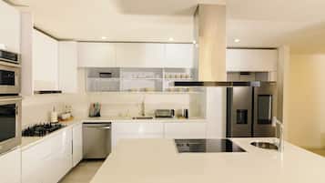 Una cocina moderna con armarios blancos, electrodomésticos de acero inoxidable y una isla central con un fregadero.