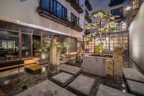 A modern indoor courtyard with stone seating, indoor plants, and a visible gym sign. - NOK Great Studio (Bogotá)