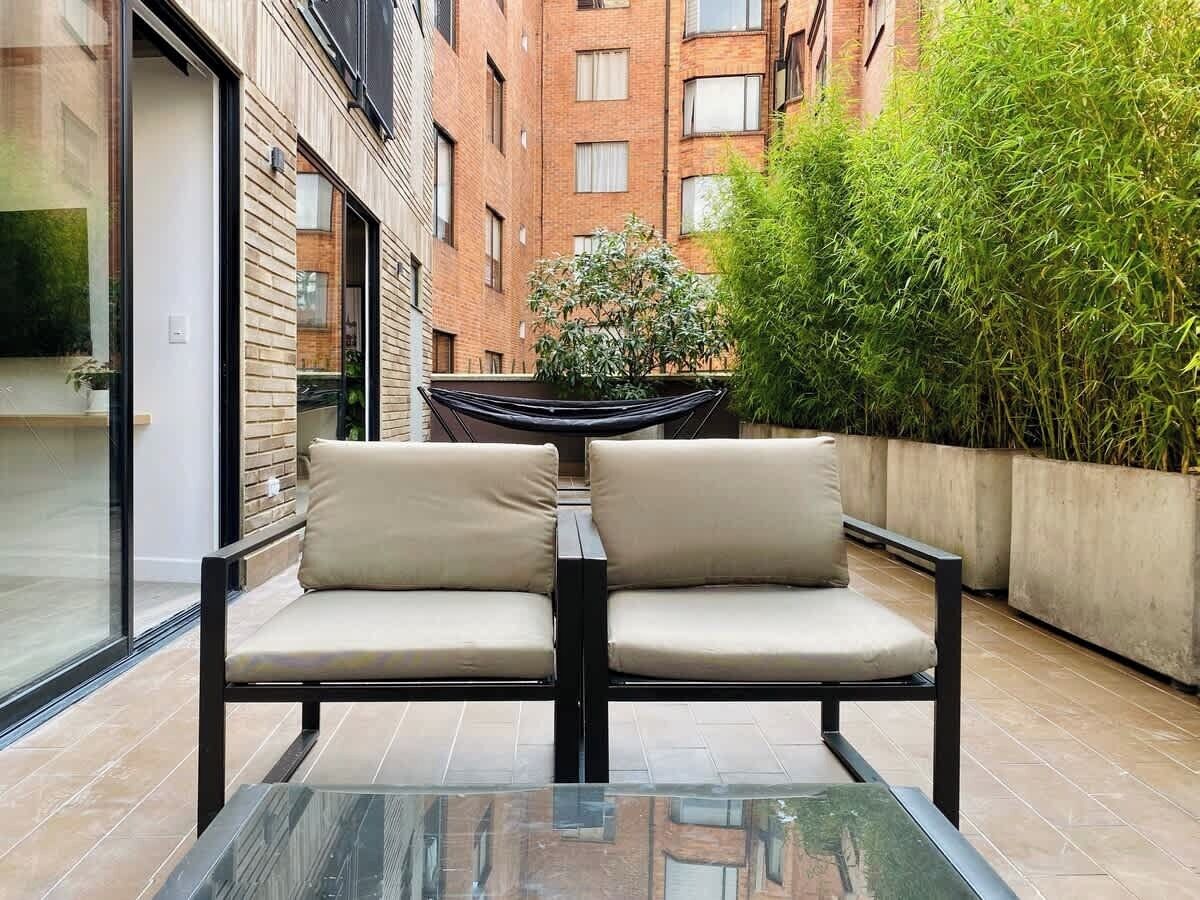 A glass-top table with two beige cushioned chairs in an outdoor patio area.