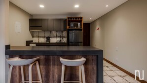 Uma cozinha moderna com uma ilha central, banquetas, micro-ondas e geladeira.