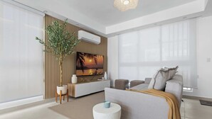 Ein modernes Wohnzimmer mit einer Couch, einem Couchtisch, einem Fernseher und einer Pflanze.