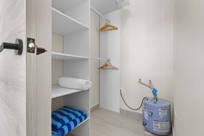 A bathroom with a white sink, a towel rack, a blue water heater, and a towel shelf. - NOK Cozy 1BR Apartment in Panorama Lake-punta Cana (Punta Cana)