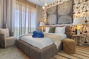Ein modernes Hotelzimmer mit einem großen Bett, zwei Nachttischen mit Lampen, Blick ins Freie und abstrakter Wandkunst.