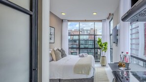 A modern hotel room with a large bed, a small kitchenette, and a view of the cityscape. - NOK Designer Studio in Chico (Bogotá)