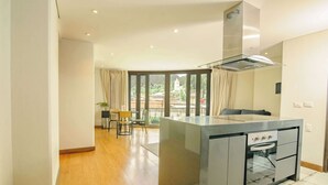 Een moderne keuken met een centraal eiland, een inbouwoven en een groot raam dat uitkijkt op een binnenplaats.