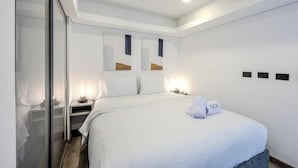 A modern hotel room with a large bed, bedside tables, and a glass partition. - NOK Luxury Loft in Chico Norte (Bogotá)