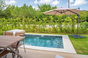 A swimming pool with a table and chairs, surrounded by greenery. - NOK Classy 3BR Villa by Vistacana Rentals (Punta Cana)