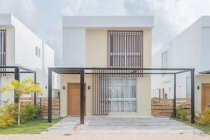 Um edifício residencial moderno com entrada central, varanda coberta e um jardim bem cuidado.