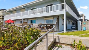 A multi-story hotel with a balcony, outdoor seating, and a wooden deck. - Beachside Ground Floor Walkout. Heated Pool. BBQ Grills ☀️ (Cocoa Beach)