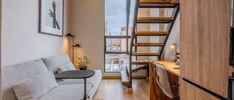 Un espace de vie moderne comprenant un canapé, une petite table, un escalier et une vue sur la ville.