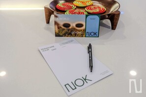 A white surface with a pen, a paper with 'REINVENT YOUR DAY' text, and a box with 'A WORLD BEYOND' and 'NUOK' branding. - NOK Beautiful 3BR Apt in Zona Rosa (Bogotá)