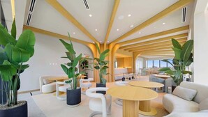 Een modern interieur met een centraal zitelement, planten in potten en uitzicht over de stad.