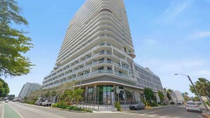 Een hoog, modern hotel met een gebogen gevel, meerdere balkons en een ruime entree.