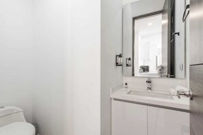 Et stilfuldt badeværelse med en hvid vask, spejl og toilet.