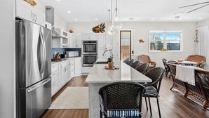 Una cocina moderna con electrodomésticos de acero inoxidable, una isla central con asientos y decoración en la pared.