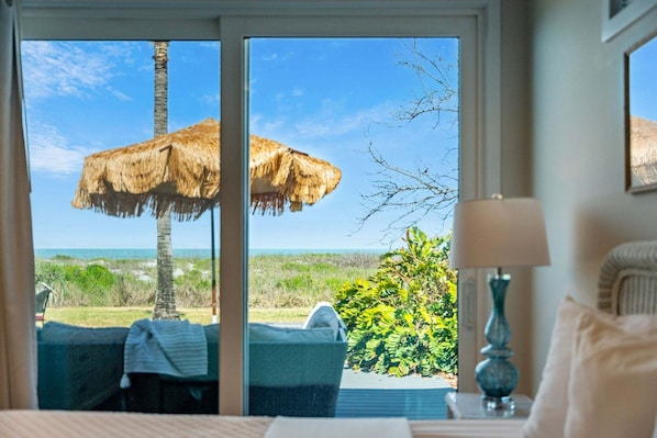 Ein Zimmer mit großem Fenster, einem Reetdachschirm, einer Couch und einer Lampe.