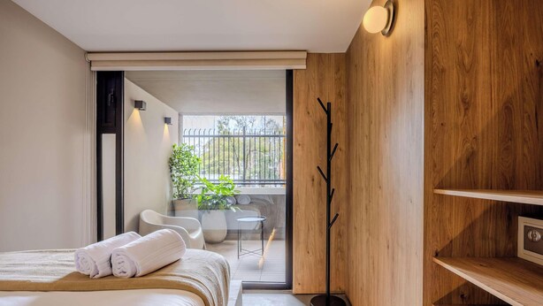 A modern bedroom with a bed, a small table, a chair, and a potted plant. - NOK Elegant 3BR Stay With Balcony at Bogota (Bogotá)