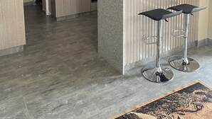 Una cucina moderna con mobili in legno, un'isola centrale con sgabelli da bar, illuminazione a sospensione e piano cottura integrato.
