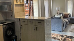 Una cucina moderna con elettrodomestici integrati, una zona pranzo con divano e un soggiorno con televisore.