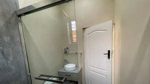 Un bagno compatto con toilette, lavabo e cabina doccia in vetro.