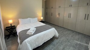Una camera d'albergo con un letto, abat-jour, un armadio e un tavolino.