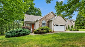 A two-story house with a stone facade, a garage, and a well-maintained lawn. - Modern Lakeview Escape: 2BR Golfers’ Retreat (Raleigh)