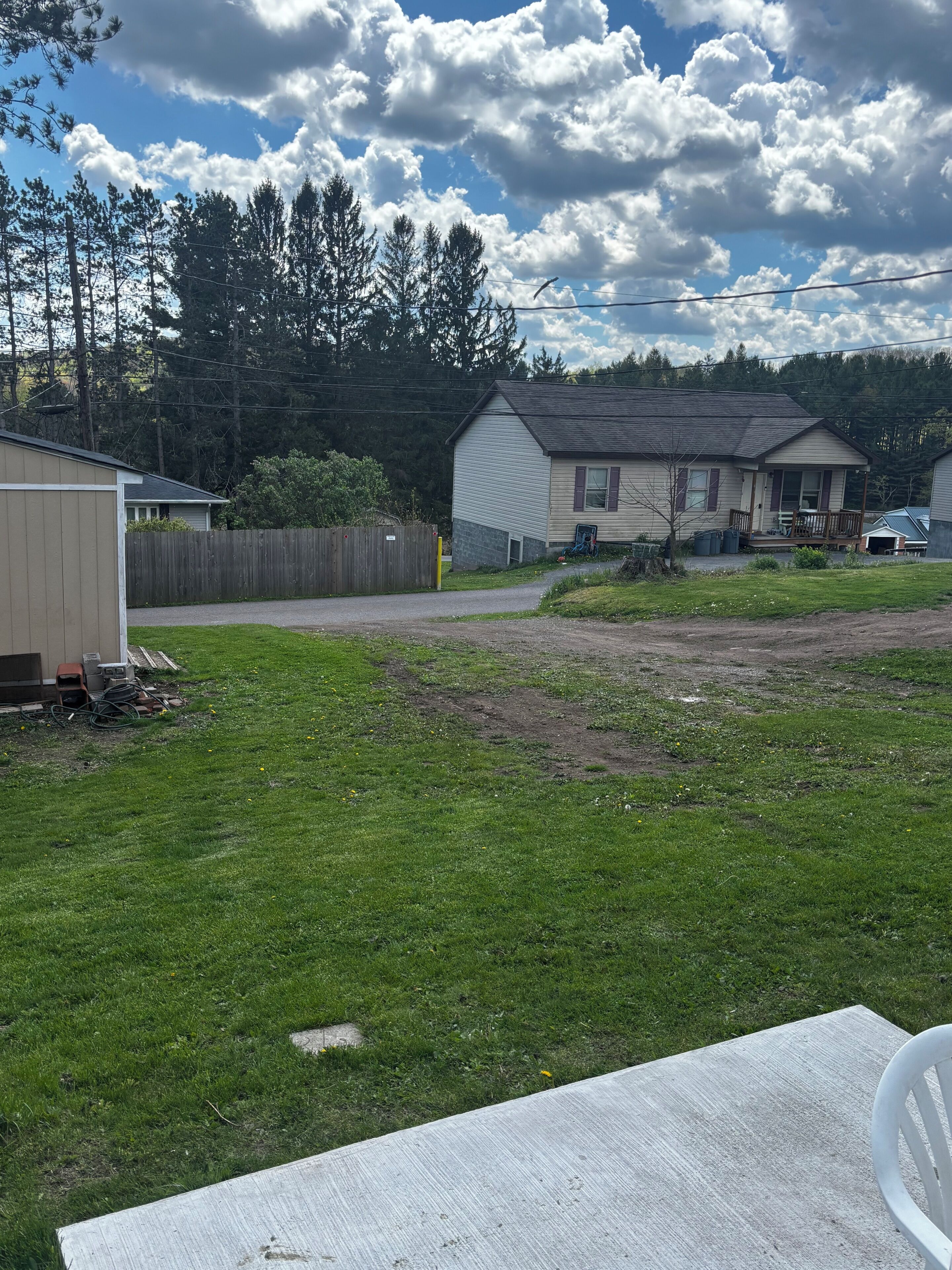 A residential area with a grassy yard, a wooden deck, and a house with a porch.