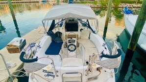 A sailboat docked at a marina with a cabin, helm station, and a 'Blown Away' sign. - Key West Sailboat Getaway (Key West)
