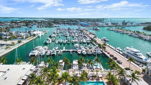 A marina with numerous boats docked, a clear blue sky, and a distant view of the coastline. - Key West Sailboat Getaway (Key West)