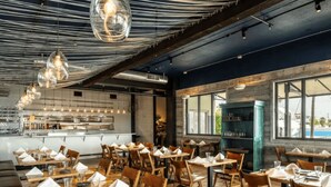 A restaurant with wooden tables and chairs, hanging pendant lights, and a view through large windows. - Key West Sailboat Getaway (Key West)